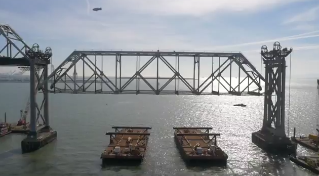 A blimp, a bridge, and waiting barges. Image: screengrab from Caltrans' live webcast of Bay Bridge takedown