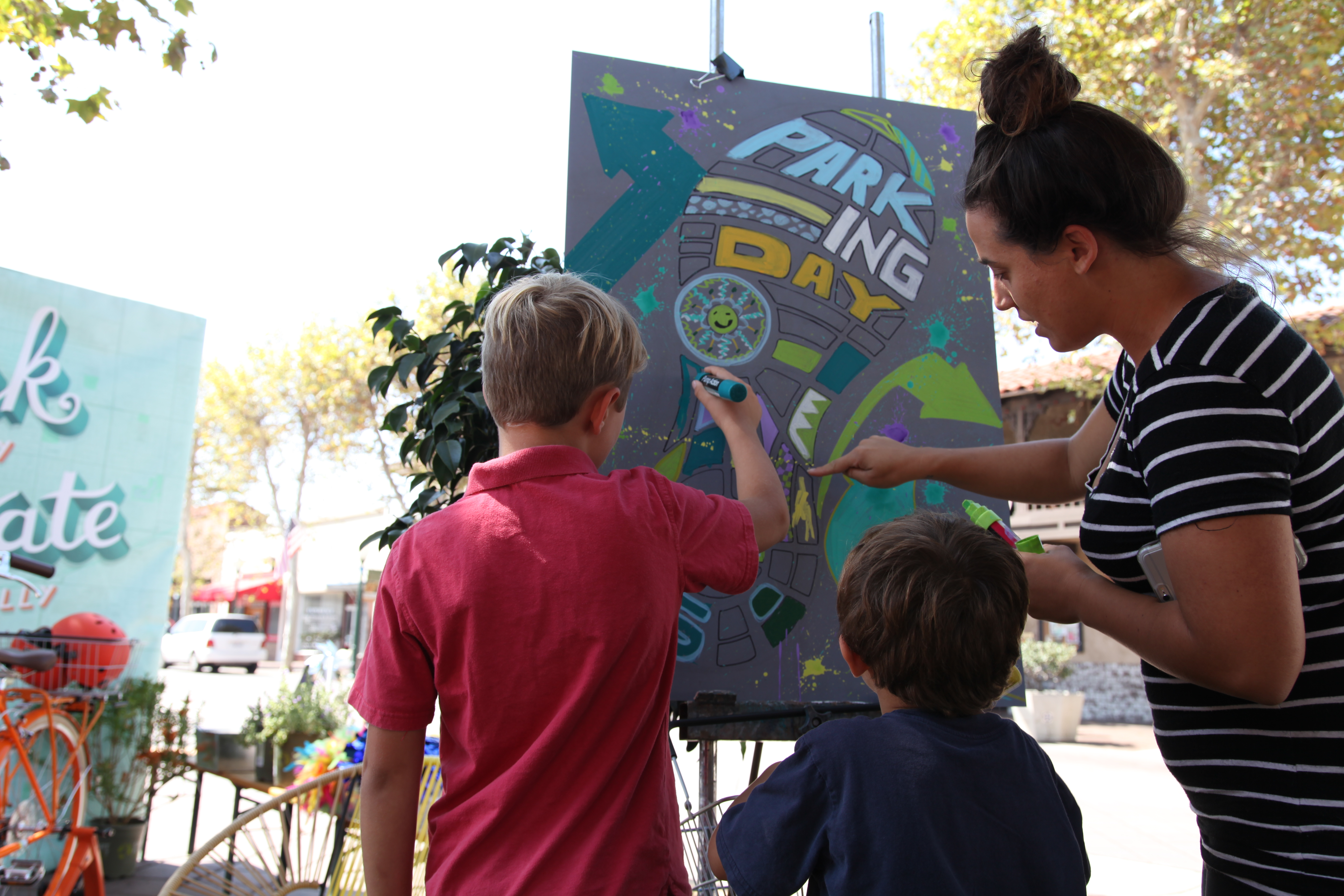 Krystin Gibson, 30, and her sons Nolan, 4, and Lynk, 7, draw on a community painting board at Orange County's Parking Day on September 17 in downtown Garden Grove. Photo by Kristopher Fortin