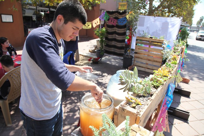 Student from Anaheim High School serving up aguas frescas to passersby. Students from Anaheim high school wanted to celebrate the city's Mexican culture and themed its booth around Dia de Los Muertos-Day of the Dead. Photo by Kristopher Fortin