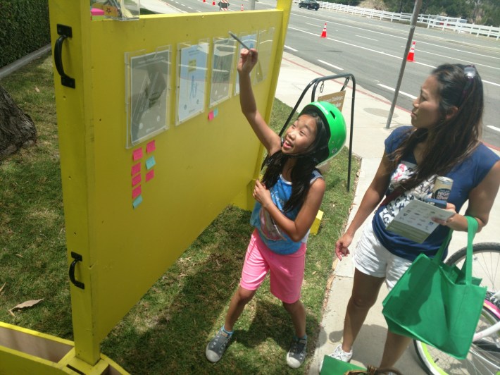 Cara Ha, left, and her mother Regina leave comments at the Go Human station next to the parking protected bike lane.