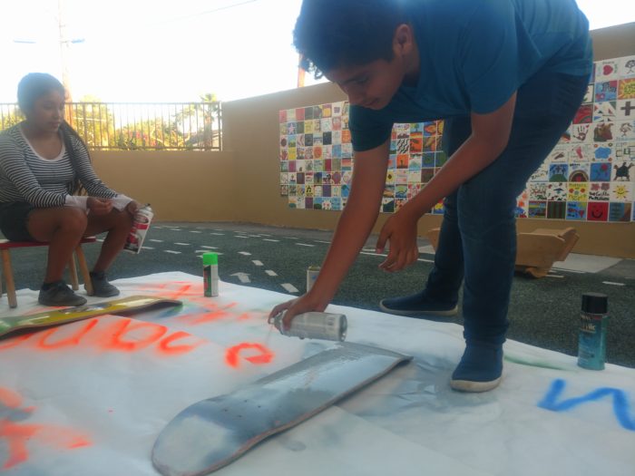 YASC youth Irma Mateo, 14 (left), and Jose Arguello, 14, paint on donated skateboards to be used in a community planning event at a vacant lot in Santa Ana. Image: Kristopher Fortin