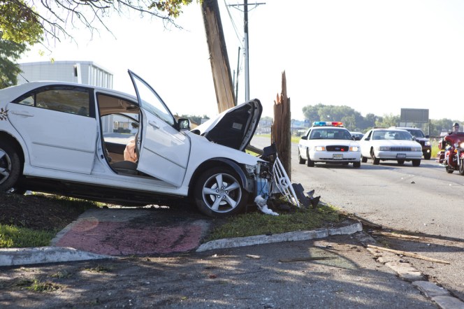 car with crumpled front end leaning into broken utility pole
