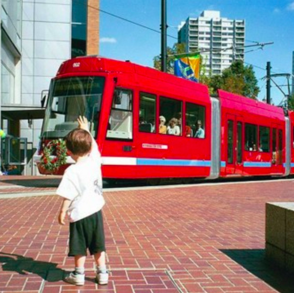 A small boy waves to a light rail train