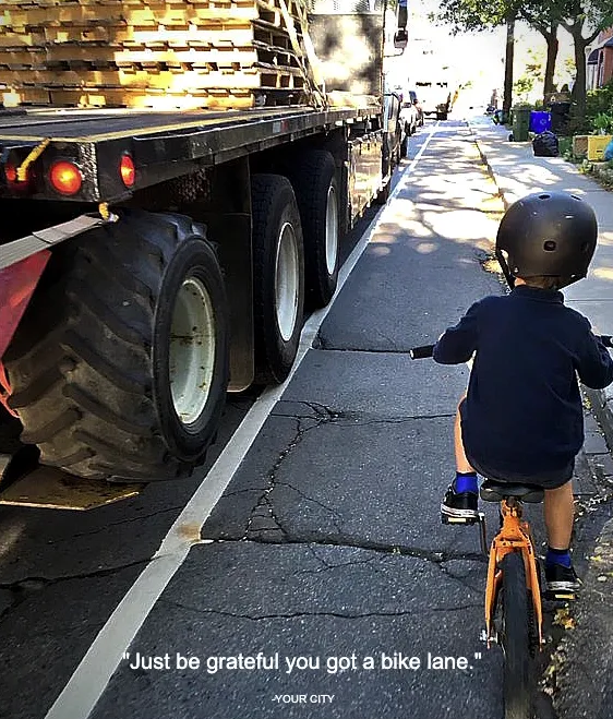 small child riding a bike in a badly paved bike lane next to a big truck