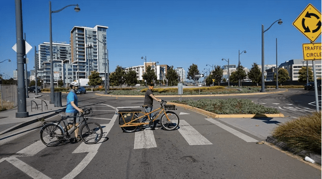 two bike riders walk their bikes in a crosswalk