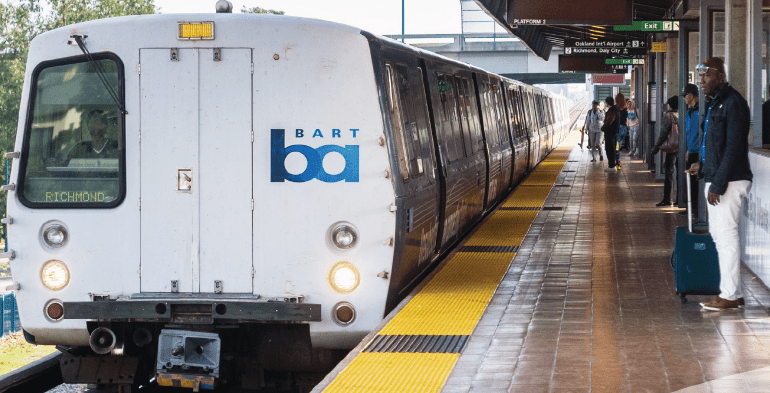 People waiting on BART platform, with BART train pulling in