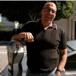 A man stands next to a parking meter