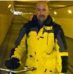 A man dressed in a yellow jacket stands in a tunnel holding a bike