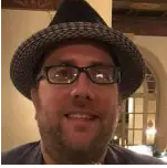 A man wears a derby hat and glasses